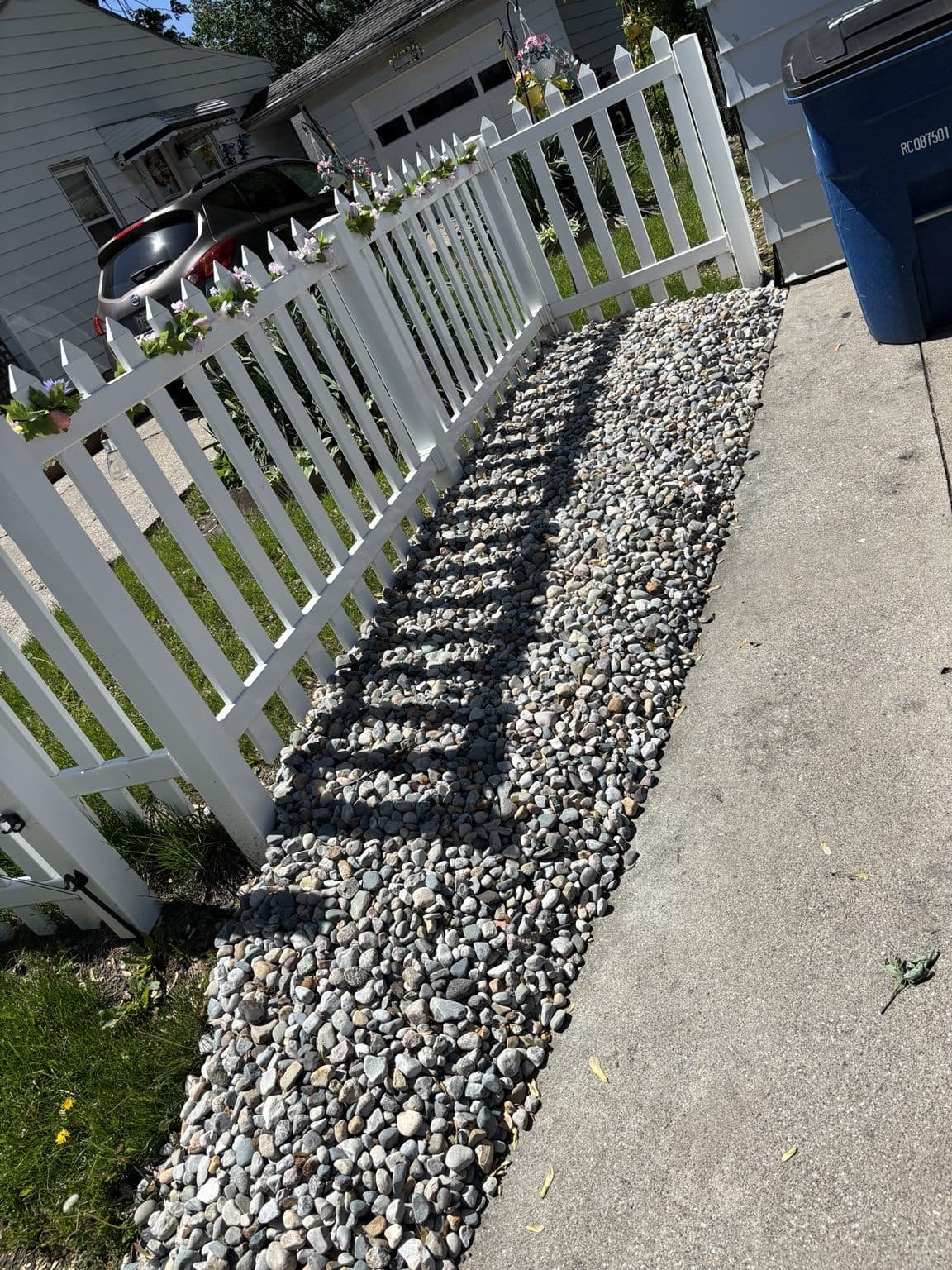 Decorative rock installed beside a walkway and white fence