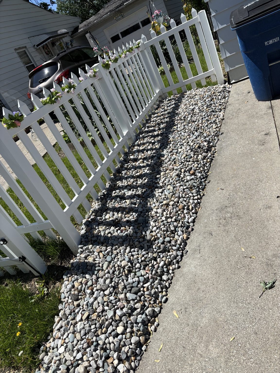 Rock installation along sidewalk and white fence